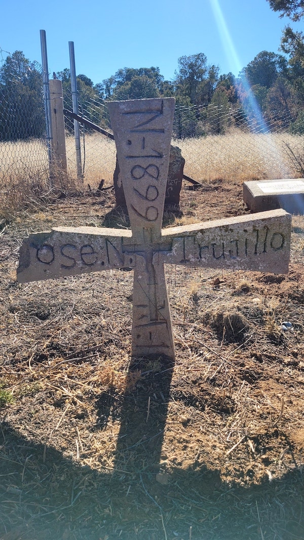 An image of a cross-shaped gravestone from 1899, which partially reads 'Jose N. Trujillo' across the center.